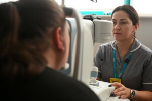 Screening practitioner examining a patient's eyes