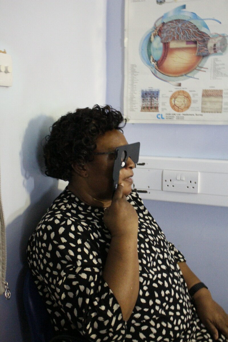 Patient holding eye screening glasses over their eyes
