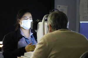 Screening practitioner examining a patient's eyes